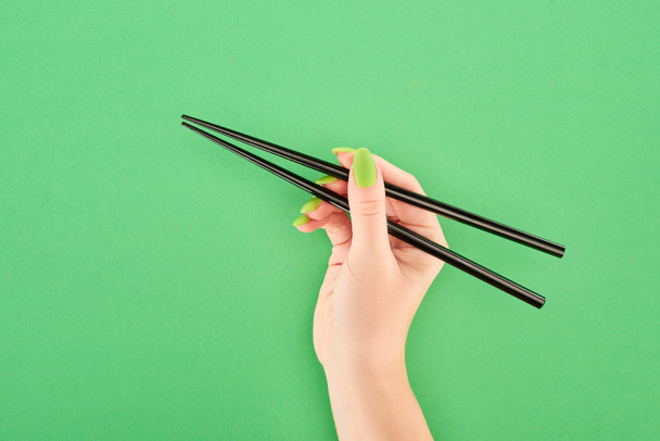 cropped view of woman holding chopsticks on green background - 写真・画像