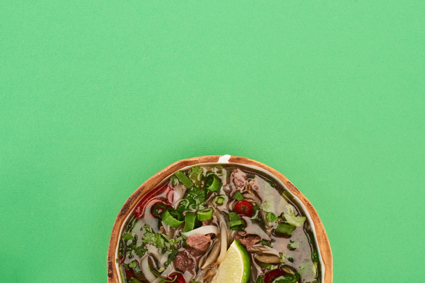 top view of pho in bowl on green background - Zdjęcie, obraz
