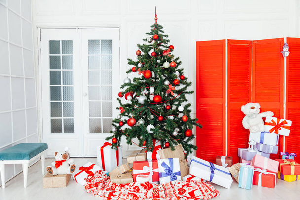 Kerstboom met rode geschenken December decor in het interieur van de witte kamer - Foto, afbeelding