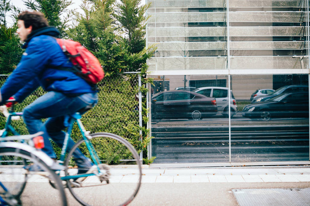 Widok z boku człowieka szybkiego ruchu na rowerze i refleksji samochodów - Zdjęcie, obraz