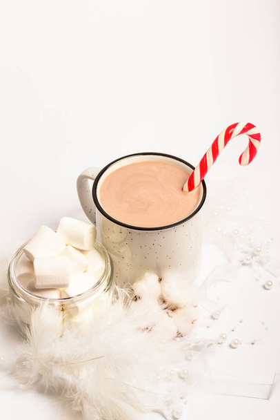 Composición navideña con una taza de cacao caliente con malvaviscos. Taza de cacao con caramelos de caña y malvaviscos están sobre un fondo blanco. Juguetes de árbol de Navidad blanco
. - Foto, imagen