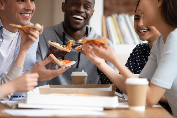 Acercamiento grupo de personas diversas sosteniendo pedazos de pizza
. - Foto, imagen