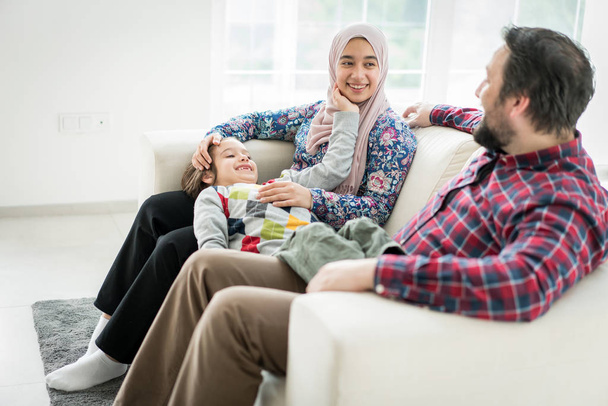 Happy Muslim family sitting on sofa in living roome at home - Photo, image