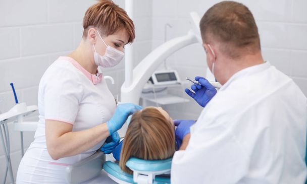 Médico dentista trata los dientes de una hermosa joven paciente
. - Foto, imagen