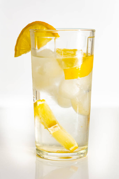 Sklenice vody s ledem a plátky citronu na bílém pozadí. - Fotografie, Obrázek