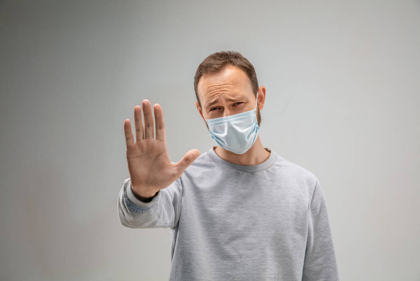 Caucasian man wearing the respiratory protection mask against air pollution and dusk on grey studio background - Photo, image