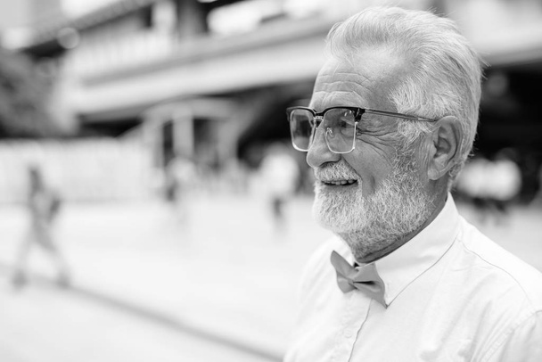 Handsome bearded senior tourist man exploring the city in black and white - Photo, Image