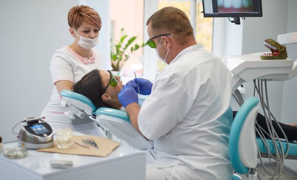 Doctor dentist treats teeth of a beautiful young girl patient. - Photo, image