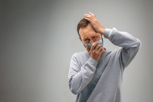 Λευκός άνδρας με μάσκα προστασίας του αναπνευστικού από την ατμοσφαιρική ρύπανση και σούρουπο σε γκρι φόντο στούντιο - Φωτογραφία, εικόνα