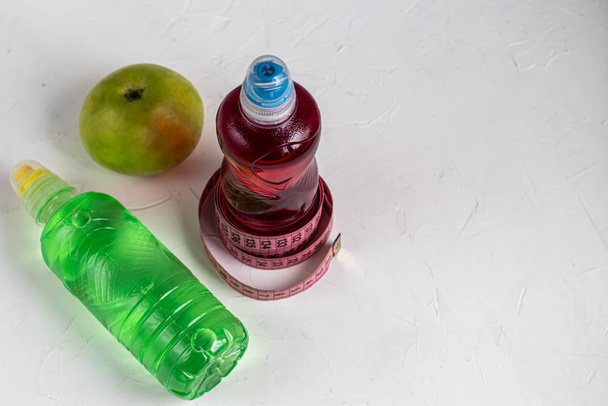 Líquido de fruta fresca para una dieta saludable. Isotónica, bebida energética. Dos botellas con agua colorida, una bebida deportiva. Apoya el equilibrio hídrico. Copiar espacio
.  - Foto, Imagen