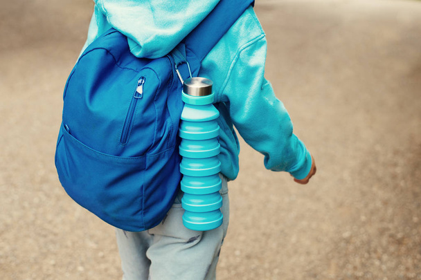 Reusable blue eco friendly water bottle on childs backpack - Fotoğraf, Görsel