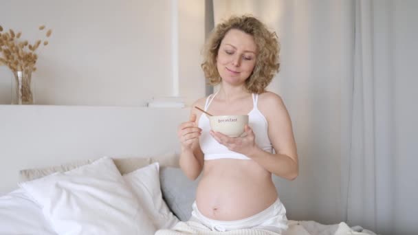 Happy Pregnant Woman Eating Cereals For Breakfast In Her Bedroom. - Materiał filmowy, wideo