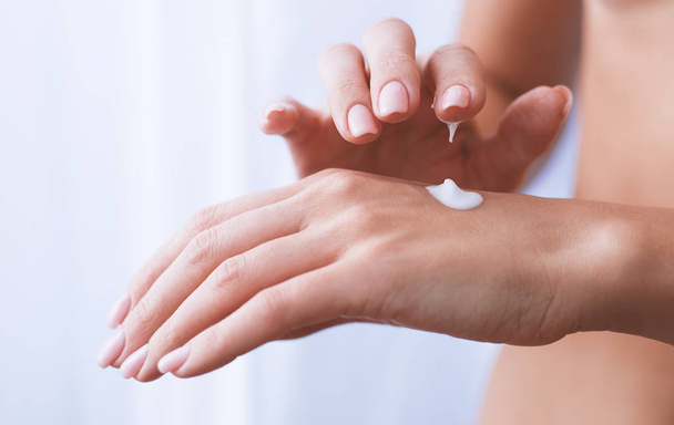 woman moisturizing her hand with cosmetic cream lotion  - Фото, изображение