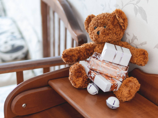 Teddy bear in kids room before New Year.. Plush toy with Christmas presents wrapped in white and golden paper.  - Foto, Imagem