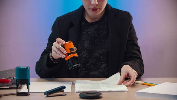 ufficio - una donna annoiata che sta per mettere un timbro arancione sul documento
 - Foto, immagini