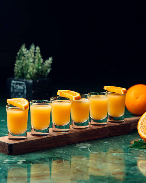 six orange cocktail shots placed on wood board - Foto, Bild