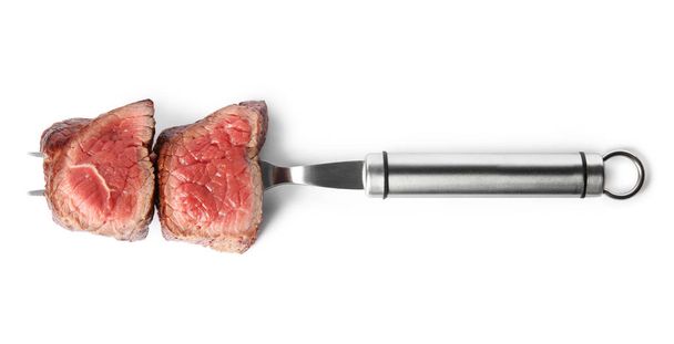 Carving fork with slices of delicious beef tenderloin isolated on white, top view - Photo, image