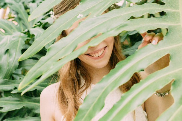 face girl peeps through palm leaves tropics - Fotografie, Obrázek