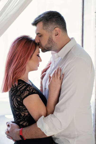 Nahaufnahme Porträt des küssenden Paares. brutaler schöner Mann küsst seine schöne Frau gegen das große Fenster - Foto, Bild