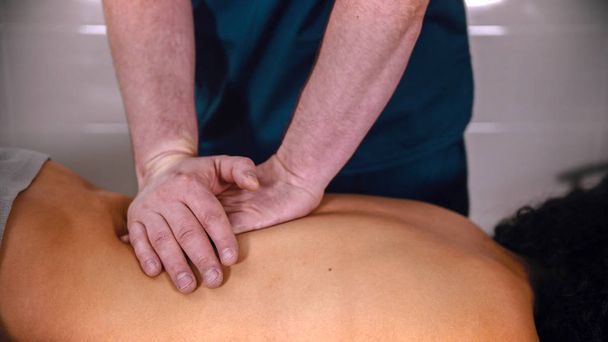Leczenie kręgosłupa - lekarz wykonujący masaż - delikatnie przyciskając dłońmi dolną część pleców - Zdjęcie, obraz
