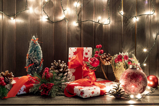 Gift boxes and garland lights over old wooden background. Christmas and new year concept. - Valokuva, kuva
