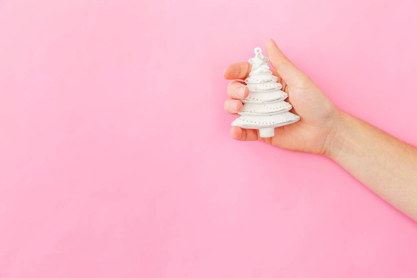 Simplesmente design mínimo mulher feminina mão segurando Natal ornamento abeto isolado no pastel rosa colorido fundo da moda
 - Foto, Imagem