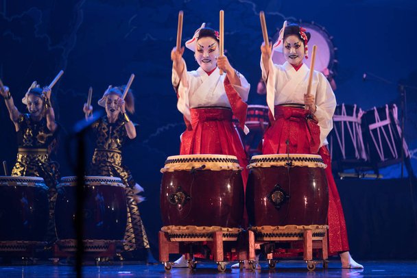 Hagyományos japán előadás. Színésznők csoportja hagyományos kimonóban és róka maszkban dob taiko dob a színpadon. - Fotó, kép