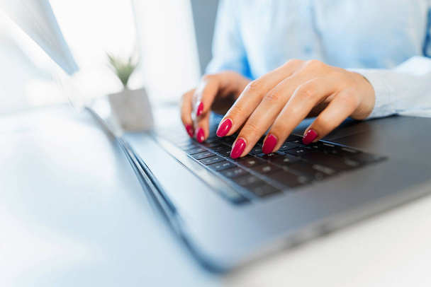 Manos femeninas con manicura brillante escribiendo en un teclado portátil
 - Foto, imagen