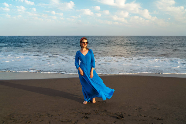 Femme en belle robe bleue sur une plage volcanique noire. Atlanti
 - Photo, image