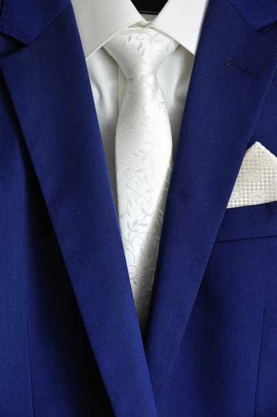 Stijlvol donkerblauw herenpak, wit shirt en witte stropdas - Foto, afbeelding