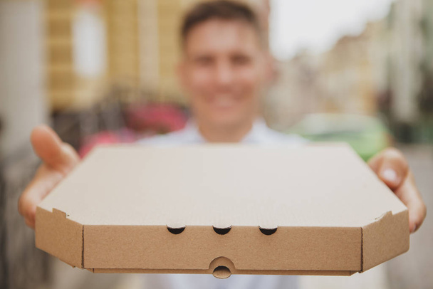 Bonito jovem andando na rua da cidade com caixa de pizza
 - Foto, Imagem