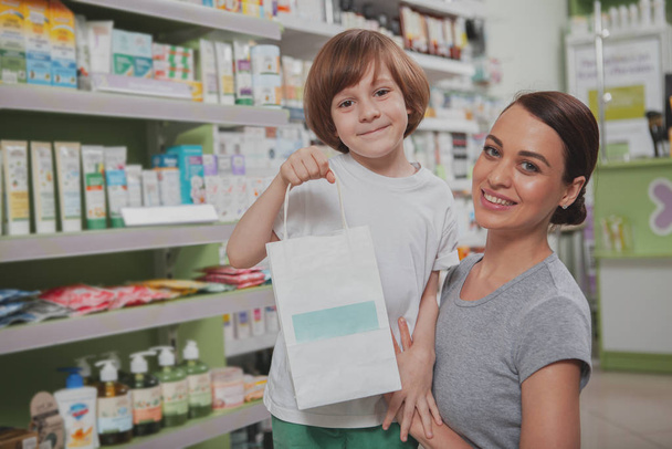 Hermosa mujer de compras en la farmacia con su hijo pequeño
 - Foto, imagen
