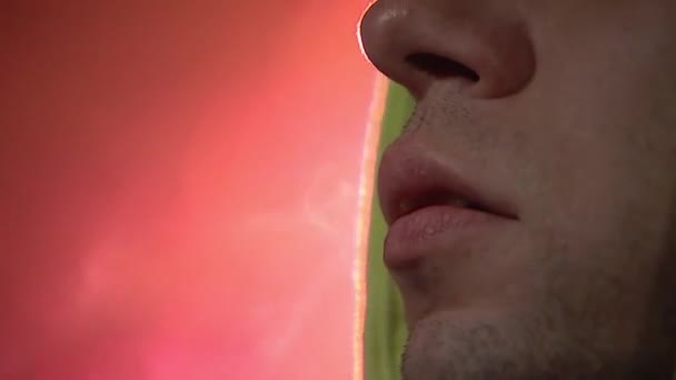 A young guy smokes a cigarette and exhales smoke, smoke fumes swirl and envelop, foggy weather, street lighting. Close-up of the face. - Footage, Video