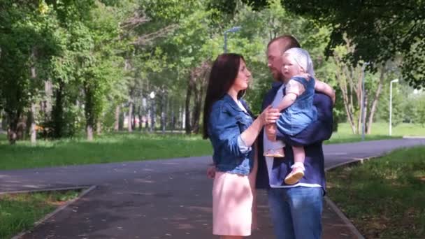 Retrato familiar en el parque de la ciudad con mamá, papá e hija bebé mirando a la cámara
. - Imágenes, Vídeo