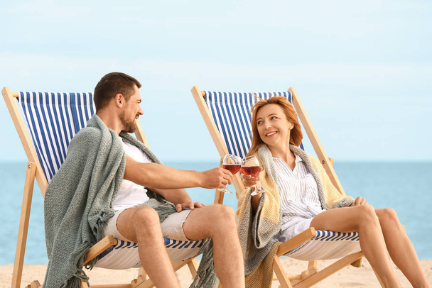 Deniz kenarında dinlenirken şarap içen mutlu çift. - Fotoğraf, Görsel