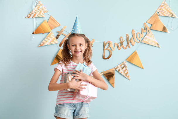 kleines Mädchen mit Geburtstagsgeschenken auf farbigem Hintergrund - Foto, Bild