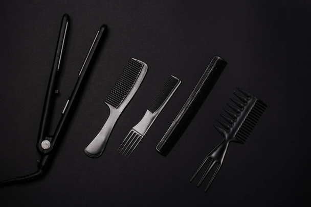Kämme und Friseurwerkzeuge auf schwarzem Hintergrund von oben - Foto, Bild