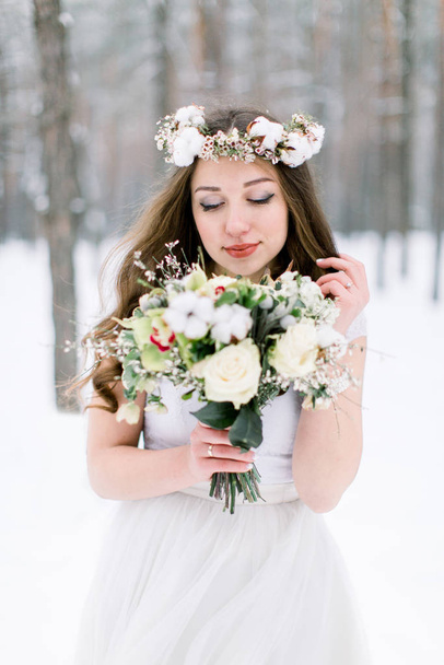Beautiful bride admiring wedding bouquet. Winter wedding. Winter wedding bouquet. - Foto, Bild