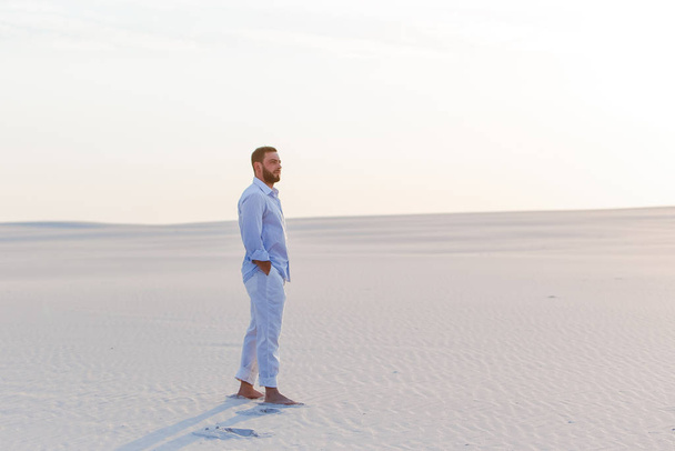 muž stojící zamyšlený pouštní košile modré kalhoty západ slunce bílý písek - Fotografie, Obrázek