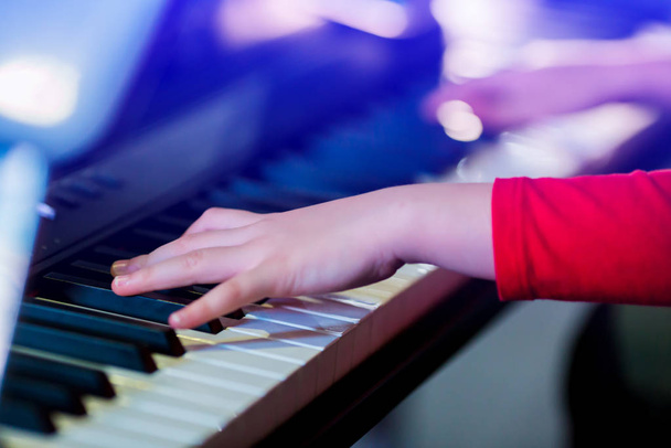 Primer plano de la mano del niño tocando el piano en el escenario con iluminación. Favoritos
 - Foto, Imagen