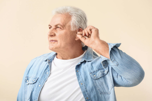 Homem maduro com aparelho auditivo em fundo claro
 - Foto, Imagem