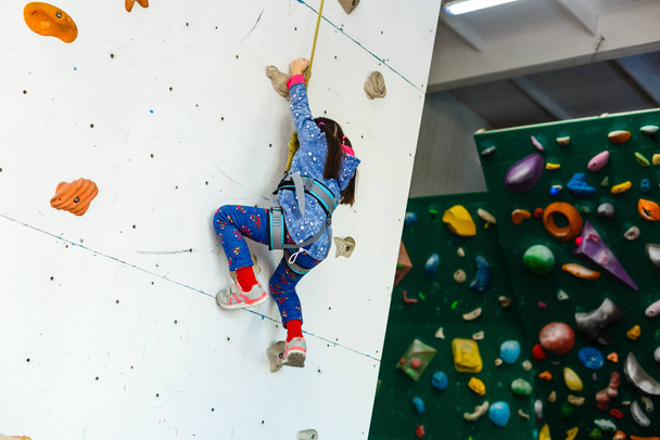 klein meisje klimmer in recreatiepark met klimwand  - Foto, afbeelding