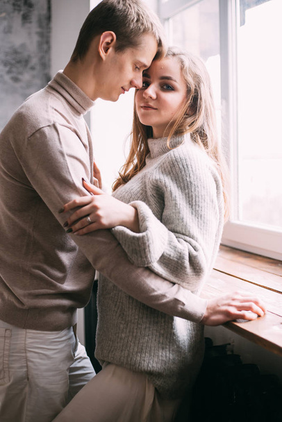 Beautiful young couple smiling while standing near the window at home - Foto, afbeelding