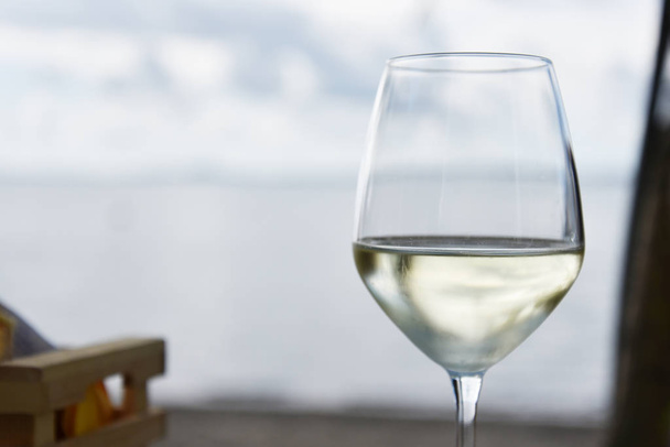 Sklenice bílého vína s jezerem nebo mořem na pozadí - Fotografie, Obrázek