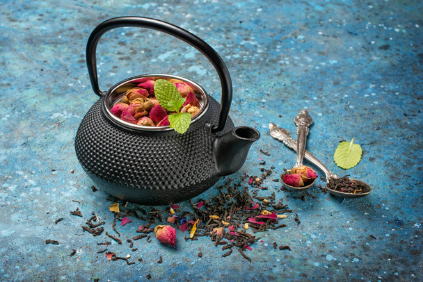 Black japanese cast iron teapot with rose tea and mint - Foto, afbeelding