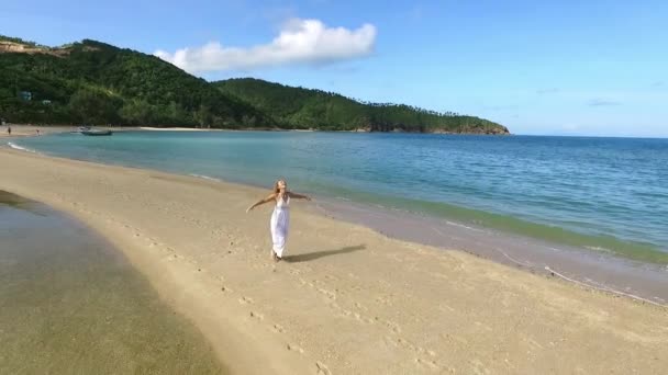 Gelukkig vrije vrouw in witte jurk draait op zand spuug op Paradise Beach. Luchtfoto. - Video