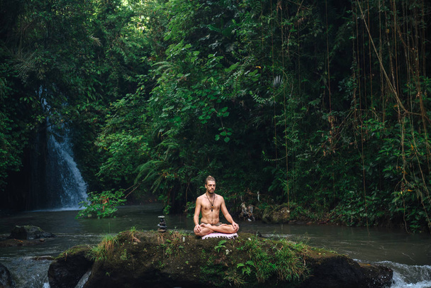 Yoga-Praxis und Meditation in der Natur. Mann übt in Flussnähe - Foto, Bild