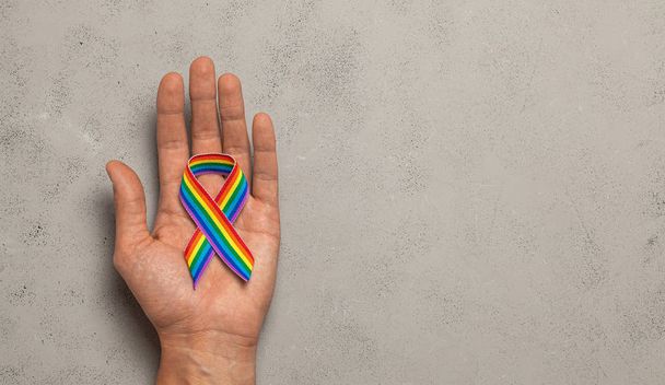 Cinta LGBT en la mano. Cinta de arco iris de orgullo en las manos de un hombre
 - Foto, imagen