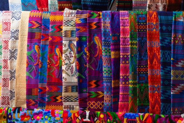 Typowe gwatemalskie tkaniny rozłożone na rynku- tkaniny o barwnych wzorach tradycyjnych gwatemalskich kwiatów - Antigua Guatemala - Zdjęcie, obraz