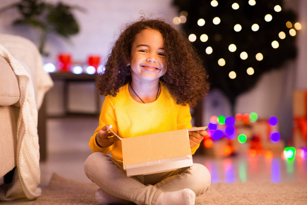 Cheerful afro girl enjoying her glowing Christmas present - Photo, Image